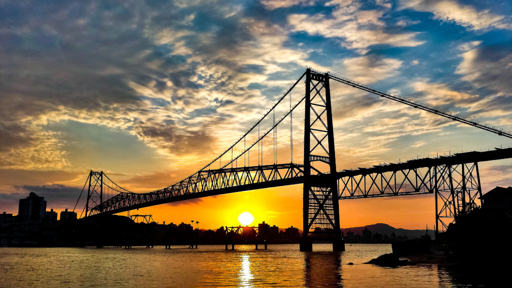 Foto da ponte Hercílio Luz com sol se pondo ao fundo